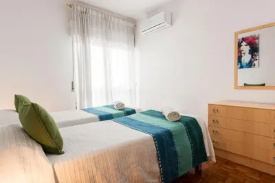 two beds in a room with a window at OLIVE - Quarteira in Quarteira