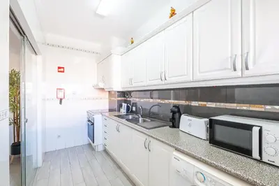 a white kitchen with a sink and a microwave at Beautifull CentralApart W/pool in Albufeira