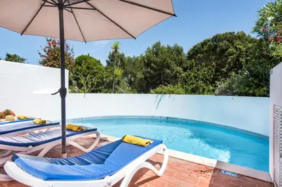 a swimming pool with two lounge chairs and an umbrella at Victory Village Beach Villa - Quinta do Lago in Quinta do Lago