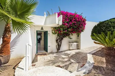 a white house with pink flowers on the wall at Victory Village Beach Villa - Quinta do Lago in Quinta do Lago