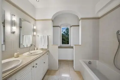 a white bathroom with two sinks and a tub and a window at Villa Casa do Amendoal by Villa Plus in Albufeira