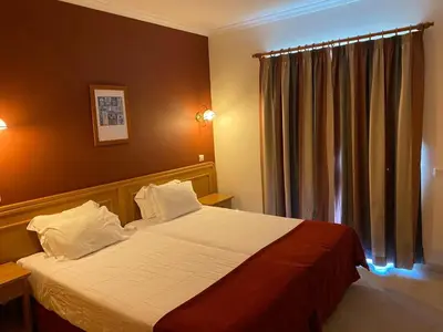 a bedroom with a bed and a window with curtains at Sunset Haven in Albufeira - Short walk to Oldtown in Albufeira
