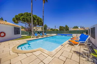 a swimming pool with lounge chairs and a villa at Villa Damasco by Villa Plus in Albufeira