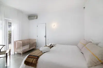 a white bedroom with a large bed and a crib at Balaia 9 in Olhos de Água
