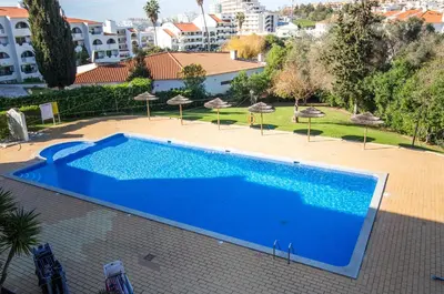 a blue swimming pool with umbrellas and a building at Apartment OuraVale in Albufeira