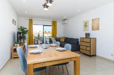 a dining room and living room with a wooden table and chairs at Apartment OuraVale in Albufeira
