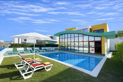 a villa with a swimming pool and two chairs and an umbrella at Marina by Check-in Portugal in Albufeira
