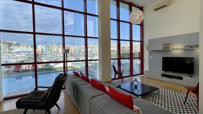 a living room with a couch and a tv and large windows at Marina by Check-in Portugal in Albufeira