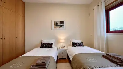 two beds in a small room with a window at Marina by Check-in Portugal in Albufeira