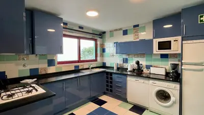 a kitchen with blue cabinets and a washing machine at Marina by Check-in Portugal in Albufeira