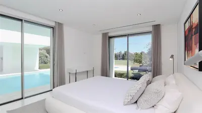 a bedroom with a white bed and large windows at Villa BEA - Clever Details, Luxury, Golf views, Sleeps 10 in Vilamoura