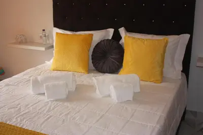 a white bed with yellow pillows and a black headboard at Yucca in Faro