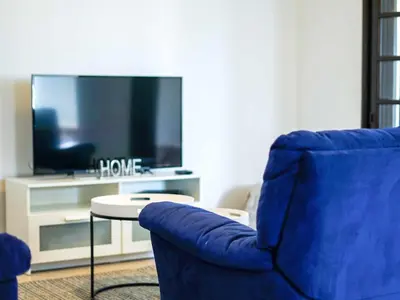 a living room with a blue chair and a tv at Villa Dogueno by Stay ici Algarve Holiday Rental in Albufeira