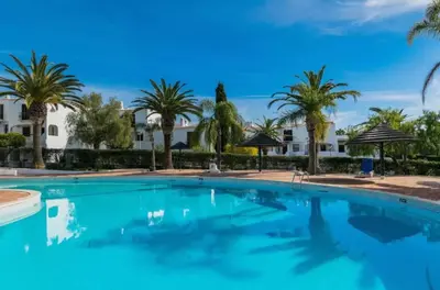 a swimming pool with palm trees in the background at Apartment Luna - Resort with a pool area with a lounge bar in Albufeira