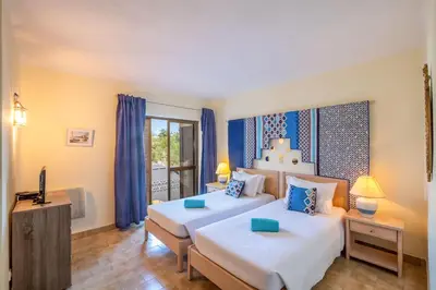 a bedroom with two beds with blue curtains at Apartment Luna - Resort with a pool area with a lounge bar in Albufeira