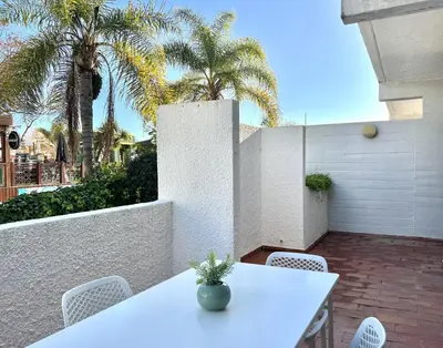 a white table and chairs on a patio with palm trees at Marina Jardim - Vilamoura Marina by HD Properties in Vilamoura