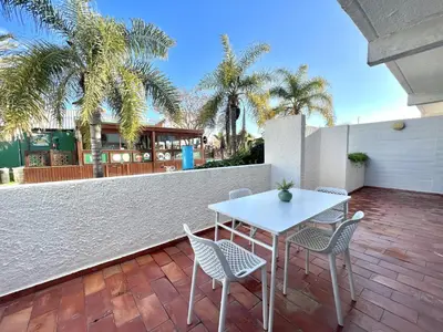 a white table and chairs on a patio with palm trees at Marina Jardim - Vilamoura Marina by HD Properties in Vilamoura