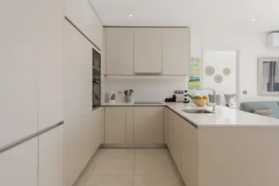 a white kitchen with white cabinets and a sink at Terraços de Quarteira Green by Real Properties in Quarteira