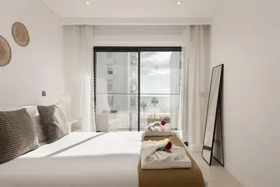 a white bedroom with two towels on a bed at Terraços de Quarteira Green by Real Properties in Quarteira