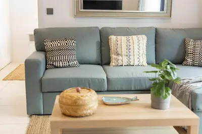a living room with a blue couch with a wooden coffee table at Terraços de Quarteira Green by Real Properties in Quarteira