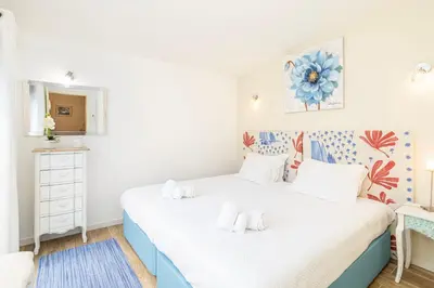 a bedroom with a white bed with a floral headboard at Centralgarve - Villa Crown 22 in Quarteira
