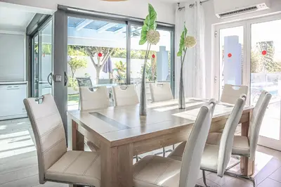 a dining room with a wooden table and white chairs at Villa Stefy by Bedzy in Galé