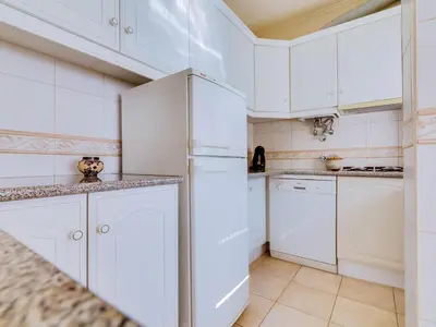 a white kitchen with white cabinets and a refrigerator at AL - Apartamento Pinhal da Praia in Vilamoura