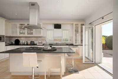 a kitchen with white cabinets and a black counter top at Villa Anna - Vale de Lobo in Faro