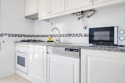 a white kitchen with a sink and a microwave at Old Town 2BR 50m Ocean w/ AC Wi-Fi Parking Terrace in Albufeira