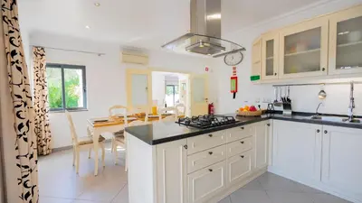 a kitchen with white cabinets and a dining room at Ocean View Villa in Boliqueime