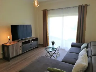 a living room with a couch and a flat screen tv at Spacieux Appartement Logis des Fées de la Marina en rez-de-chaussée de chaussée in Albufeira