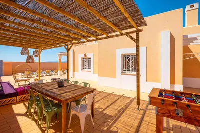 a patio with a wooden table and chairs at Villa Habitate - pool fence & heating beach bars in Albufeira