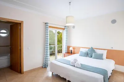 a bedroom with a large white bed and a window at Apartment Hugo - Complex perfect for families in Albufeira