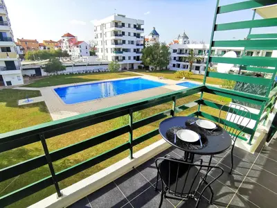 a balcony with a table and a swimming pool at Vilamoura Neptuno in Quarteira