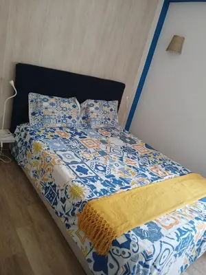 a bed with a blue and white comforter and pillows at AZULEJOS em VILAMOURA PORTUGAL in Vilamoura