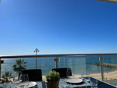 a table with wine glasses and a view of the beach at Pure Sea - Beach Apartment in Quarteira