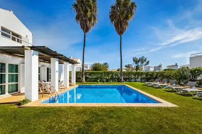 a swimming pool in the yard of a house with palm trees at Villa Luz do Atlantico by OCvillas in Galé