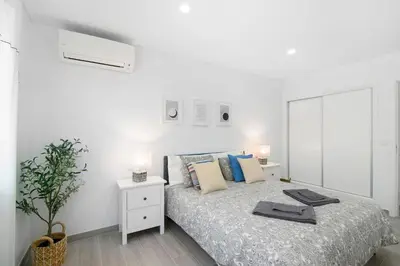 a white bedroom with a bed and a mirror at Apartamento Acácia in Vale do Lobo