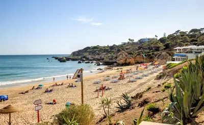 a beach with people laying on the sand and the ocean at Luxury Apartment with Pool in Albufeira