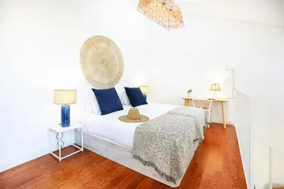 a white bedroom with a bed with blue pillows at Watermelon Sugar Apartment in Faro