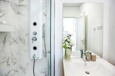 a white bathroom with a sink and a shower at Under the moon in Faro