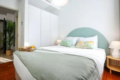 a bedroom with a large bed with a green headboard at Under the moon in Faro