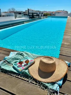 a hat and a tray of food next to a swimming pool at Prime Lux Albufeira in Albufeira