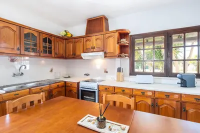 a kitchen with wooden cabinets and a wooden table at Patroves Ranch - private pool & sea views in Albufeira