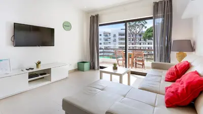 a living room with a white couch and a tv at Sweet As by LovelyStay in Quarteira