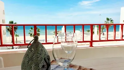 a table with two wine glasses and a bag on a balcony at Seaside Serenity: 1BR with Breathtaking Ocean View in Quarteira
