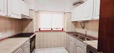 a kitchen with white cabinets and a sink and a window at Seaside Serenity: 1BR with Breathtaking Ocean View in Quarteira