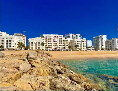 a group of buildings on a beach next to the ocean at Seaside Serenity: 1BR with Breathtaking Ocean View in Quarteira