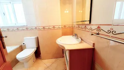 a bathroom with a sink and a toilet and a mirror at Quarteira Beach Vacation: 2BR steps to the sand in Quarteira