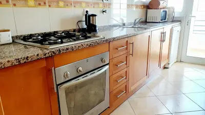 a kitchen with a stove and a counter top at Quarteira Beach Vacation: 2BR steps to the sand in Quarteira
